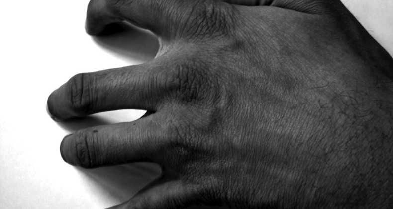 Angry man scrapes fingernails on desk