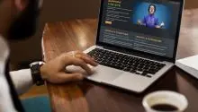 Man drinking coffee while reading about joomla on a laptop