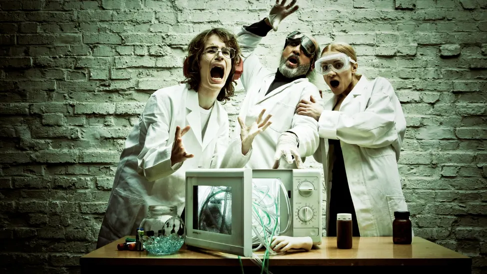 three mad scientists iin lab coats screaming over an exploading microwave oven