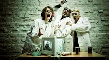three mad scientists iin lab coats screaming over an exploading microwave oven