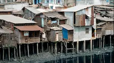 slum housing built on poles above waste land