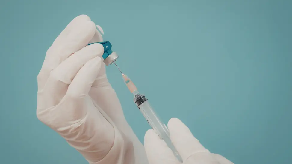 Gloved hands preparing injection
