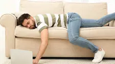 lazy man relaxed on sofa using a latop on the floor