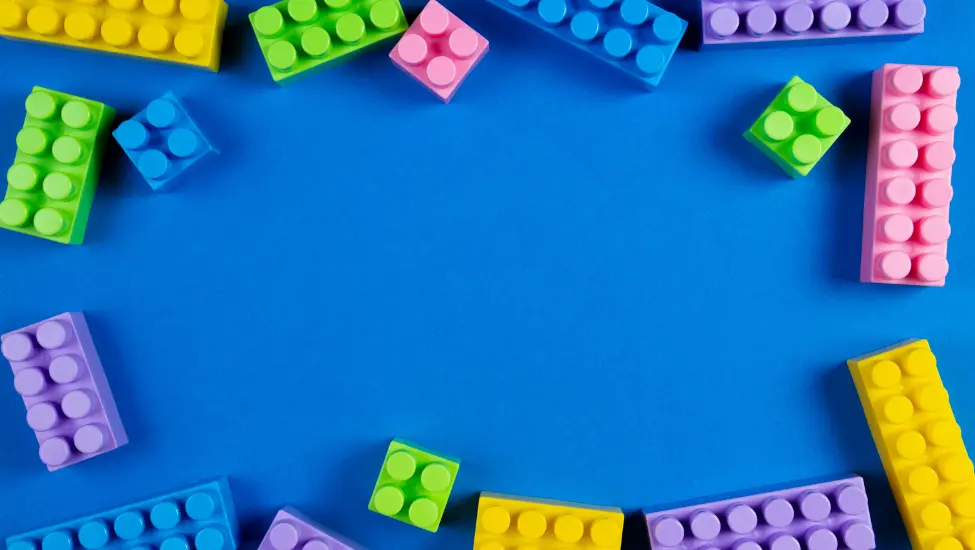 assorted colour lego building bricks around the edges of a blue background 