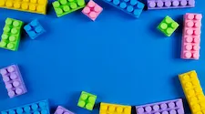 assorted colour lego building bricks around the edges of a blue background 