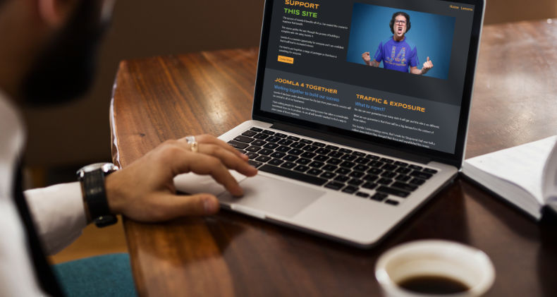 Man drinking coffee while reading about joomla on a laptop