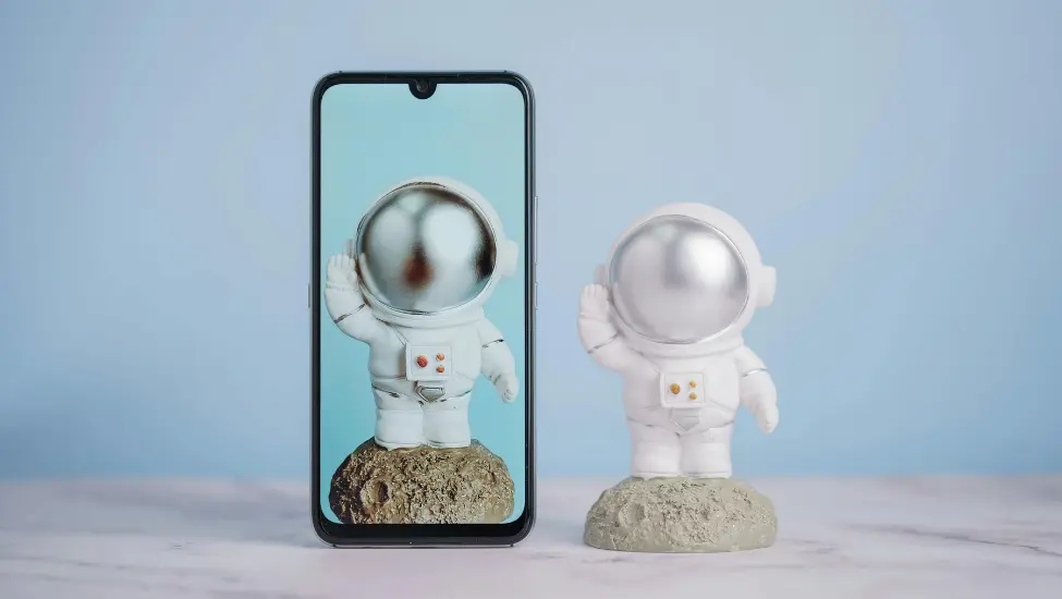model of a man on the moon with an identical copy on a phone