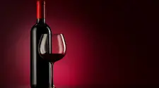 Bottle of red wine and a glass that is either half full or half empty